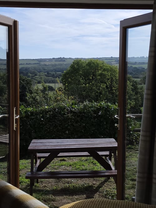 View from Valley View room at Ailwood Farm Stay showing wooden picnic table on terrace overlooking Dorset countryside near