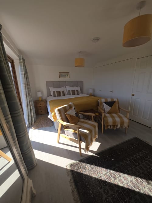 Modern bedroom at Ailwood Farm Stay in Dorset with double bed, seating area, and natural light from window