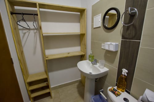 Baño en Vamos pa San Andrés Isla con lavamanos tipo pedestal, estantes de madera, espejos y artículos de tocador