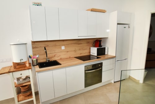 Cocina moderna con gabinetes blancos, encimeras de madera, horno empotrado y electrodomésticos de acero inoxidable en Sunset House, El