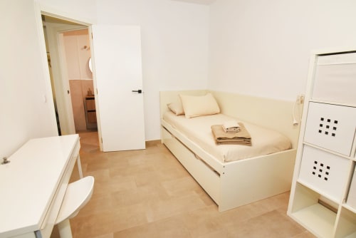Dormitorio luminoso en Sunset House de Angi Holiday Lettings en El Cotillo con cama color crema, suelo de madera y acceso al baño