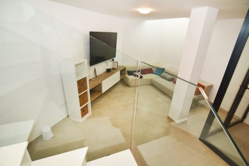 Sala de estar moderna con televisor, muebles de madera y vistas al mar en Sunset House, El Cotillo