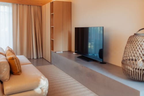 Sala de estar de villa moderna en Quinta Das Pirâmides con sofá de cuero, televisor, muebles de madera y vistas a las montañas en Vila Nova de