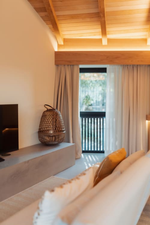 Sala de estar moderna en Quinta Das Pirâmides con lámpara tejida, sofá color crema, vigas de madera y vistas a la montaña