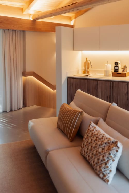 Acogedora sala de estar de la villa Quinta Das Pirâmides con sofá beige, vigas de madera y cocina americana en Vila Nova de Famalicão