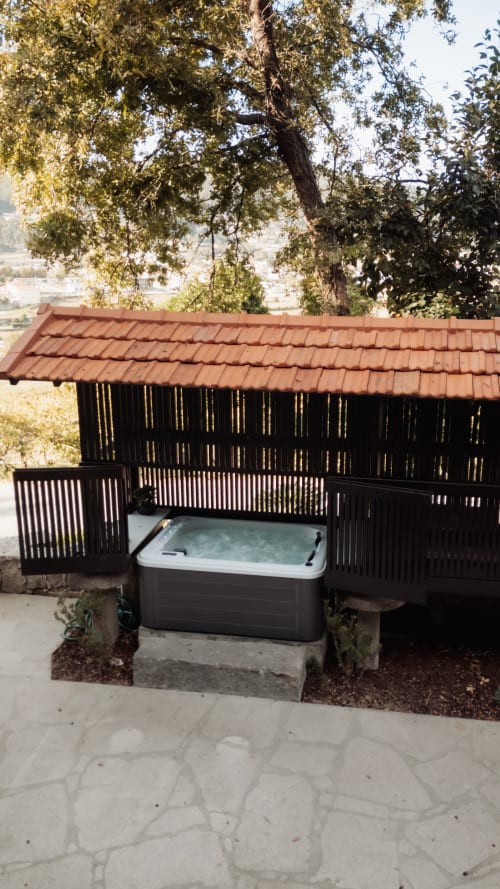 Bañera de hidromasaje en terraza bajo pabellón de madera con vistas a la montaña en la villa Quinta Das Pirâmides, Vila Nova de Famalicão