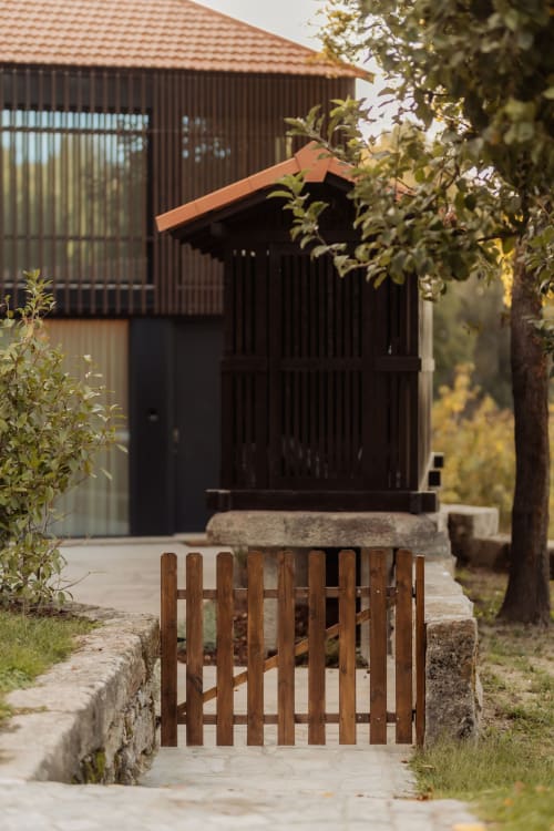 Entrada de puerta de madera a la villa Celeiro en Quinta Das Pirâmides, Vila Nova de Famalicão, con arquitectura moderna negra