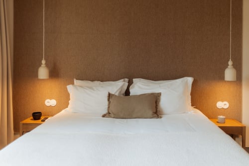 Cómodo dormitorio en villa Quinta Das Pirâmides con ropa de cama blanca, lámparas colgantes, papel tapiz espiga y decoración moderna