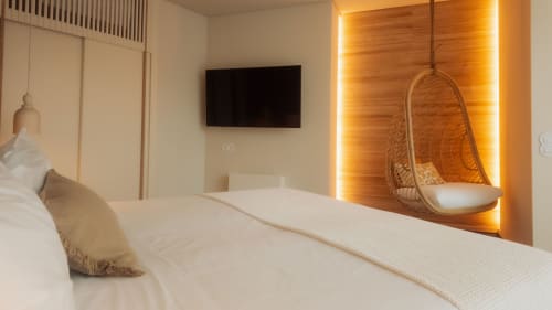 Dormitorio moderno en la villa Quinta Das Pirâmides con cama blanca, silla colgante, TV de pared e iluminación ambiental cálida