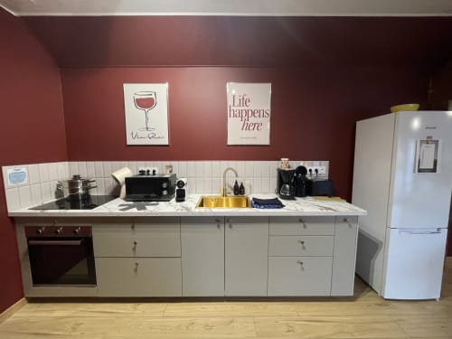Cuisine contemporaine du gîte Le Clos d'Émilie aux armoires blanches, plan de travail en marbre et murs bordeaux à Saint-Marcel