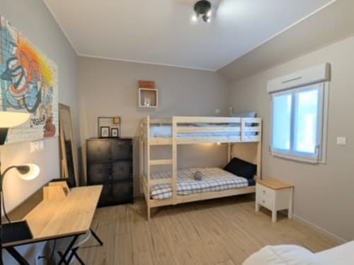 Chambre lumineuse du cottage Le Clos d'Émilie avec lits superposés, bureau en bois et grande fenêtre à Saint-Marcel