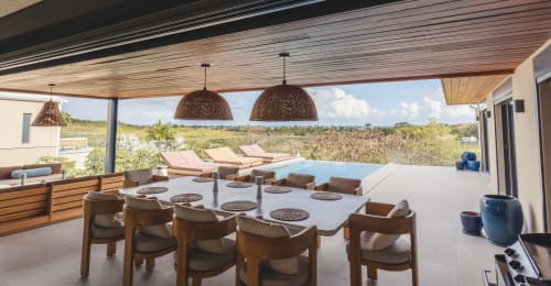 Terrasse couverte moderne de la Collection Blue Horizon Saint-François avec table à manger, chaises en bois, luminaires suspendus et vue océan