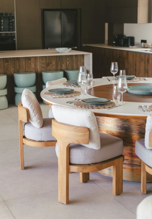 Ambiance de salle à manger moderne à Blue Horizon Collection avec chaises en bois, coussins blancs, couverts dressés et cuisine