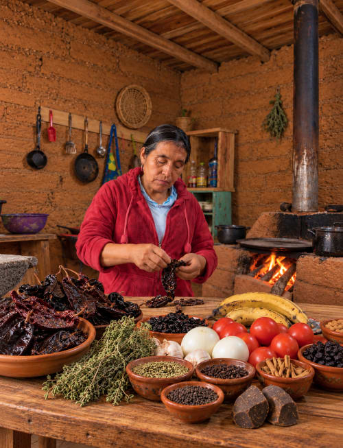 Mujer preparando ingredientes tradicionales mexicanos en la cocina rústica del hotel Sento SanMa, San Mateo Rio Hondo
