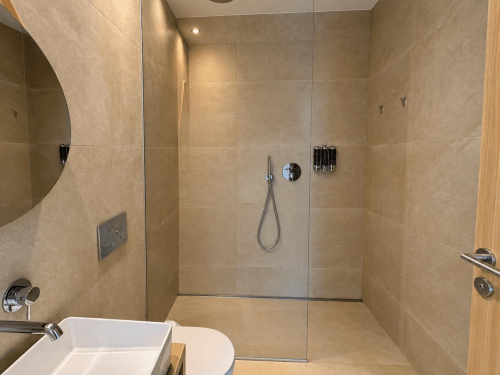 Moderno baño con ducha de azulejos beige y cabina de cristal en el apartamento Holibai de Baiona