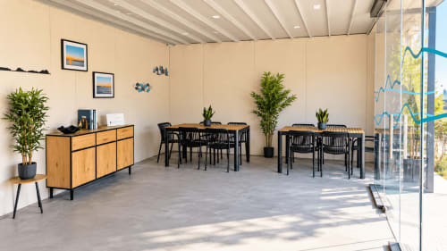 Acogedora sala de estar del apartamento Holibai en Baiona con mesas de comedor, sillas negras, muebles de madera, plantas y acceso a terraza
