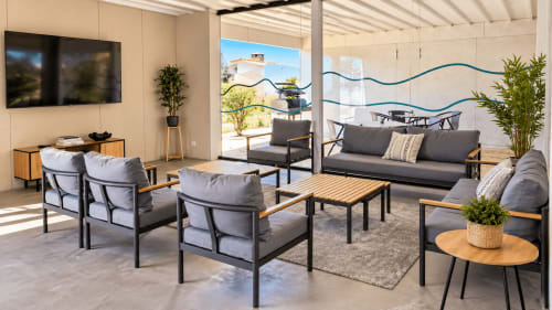 Salón moderno con asientos grises, mesas de madera y vistas a la terraza en el apartamento Holibai de Baiona