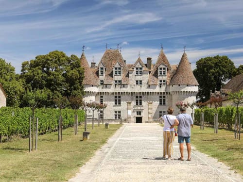Pareja caminando hacia el Château Alto Cormeil, un alojamiento rural estilo castillo medieval en Saint-Émilion con viñedos