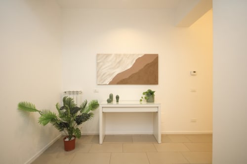 Ingresso di appartamento moderno a Palermo con scrivania bianca, pianta di palma in vaso, arte murale e arredamento minimalista