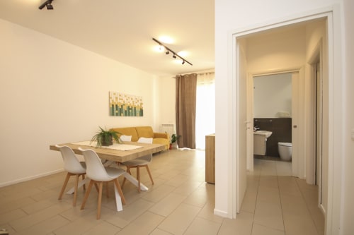 Modern Palermo apartment living room with dining table, yellow sofa, and bathroom entrance