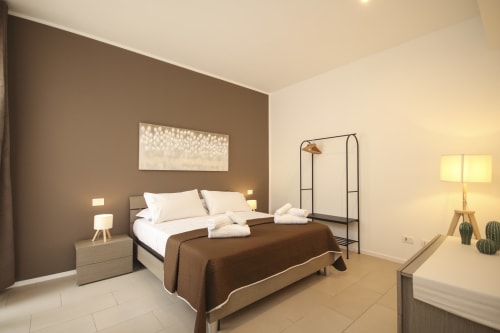 Deluxe bedroom with canopy bed, brown accent wall, and modern furnishings at Location 10 Agency, Palermo