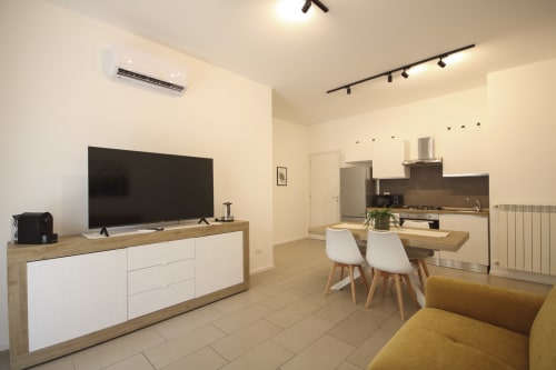 Modern Palermo apartment with open-plan living, kitchen, dining area, TV entertainment unit, and yellow accent seating