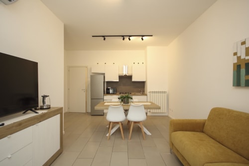 Modern open-plan Palermo apartment with kitchen, dining table, seating area, flat-screen TV, and warm décor