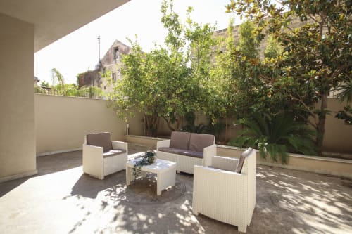 Deluxe apartment terrace in Palermo with white wicker seating, potted plants, and city views