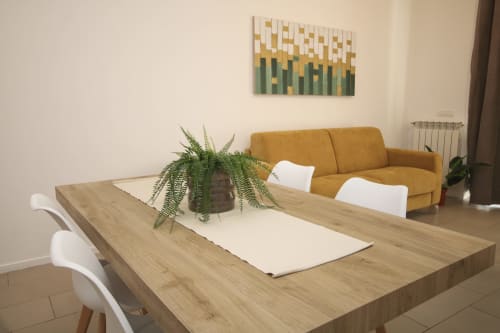 Modern living room in Palermo apartment with wooden dining table, mustard sofa, green plant, and abstract wall art