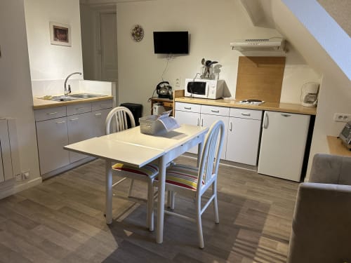 Cuisine et coin repas moderne du studio à Hébergement Luxeuil Les Bains avec table blanche et kitchenette équipée