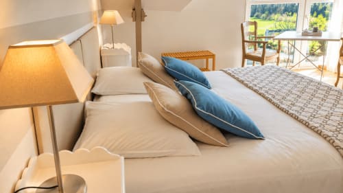 Chambre Armor à Ty Coz Breizh, Guidel, avec lit double, coussins bleus et beige et coin bureau lumineux donnant sur le jardin.