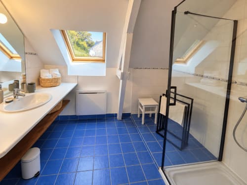 Salle de bain privative de la chambre Armor à Ty Coz Breizh, Guidel, avec douche vitrée, carrelage bleu et lumière naturelle.