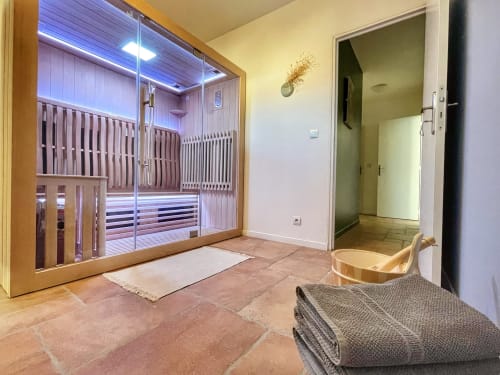 Luxueuse salle de spa aux Chambres d'hôtes la Soulenque avec sauna, baignoire en bois et carrelage en terre cuite à Capestang