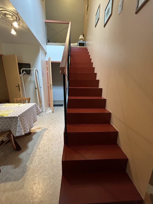 Escalier rouge menant à l'étage supérieur dans l'appartement Le Duplex 1 à l'Hébergement Luxeuil Les Bains