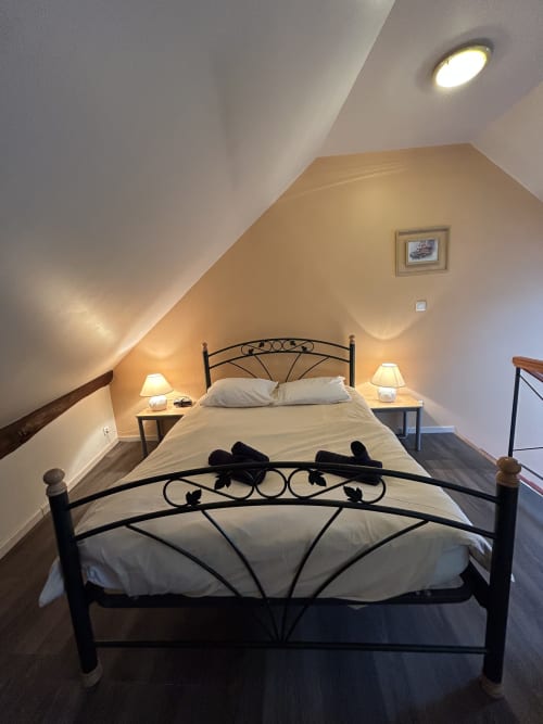 Chambre mansardée cosy à l'Hébergement Luxeuil Les Bains avec lit en fer forgé, ambiance chaleureuse et plafond oblique