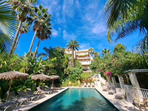 Piscine de luxe de la Résidence Vélès Plage à Cannes avec palmiers, transats et architecture de villa méditerranéenne