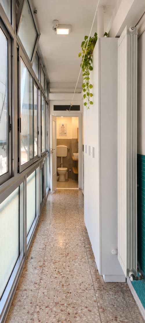 Corridoio stretto e luminoso a Easystay Bari con finestre, pianta sospesa, radiatore e ingresso bagno