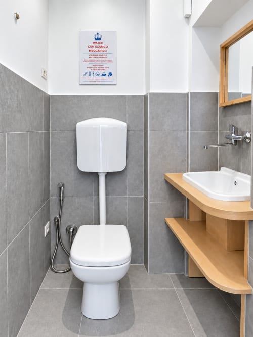 Bagno moderno a Easystay Bari con wc bianco, mobile lavabo in legno, piastrelle grigie e bidet a Bari, Italia