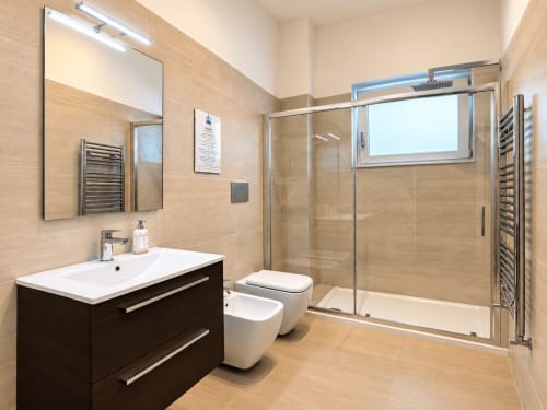 Bagno moderno presso Easystay Bari con piastrelle in legno, box doccia in vetro e vanity scuro