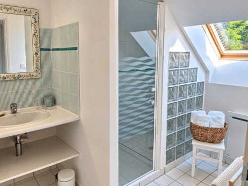 Salle de bain privative de la chambre Argoat à Guidel, avec douche vitrée, vasque, fenêtre de toit et linge de toilette.