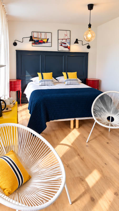 Vue d'ensemble de la chambre familiale Heol à Guidel, avec grand lit, fauteuils blancs, décoration marine et lumière naturelle.