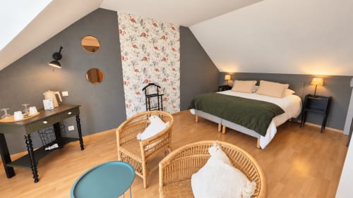 Chambre mansardée de la maison d'hôtes Ty Coz Breizh à Guidel, France, avec lit, fauteuils en rotin et mur d'accent à motifs