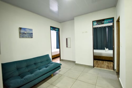Amplia sala de estar de la cabaña en Vamos pa San Andrés Isla con sofá verde azulado, entrada a dormitorio y comodidades modernas