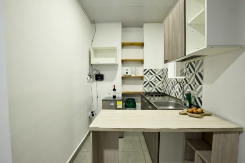 Moderna cocina compacta en Apto 301 de Vamos pa San Andrés Isla, con muebles blancos, backsplash geométrico y acero inoxidable