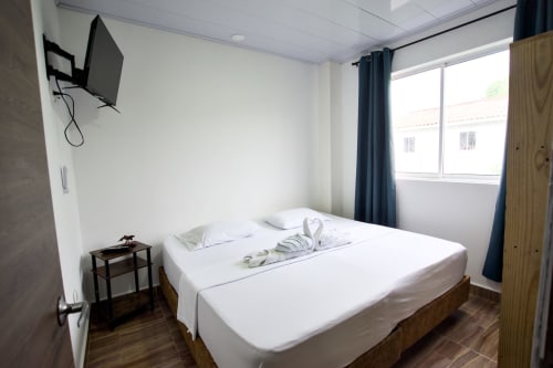 Dormitorio moderno en la cabaña Vamos pa San Andrés Isla con cama queen, TV de pared y ventanas con vistas a la montaña