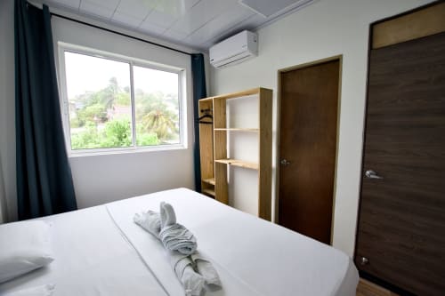 Moderno dormitorio en Vamos pa San Andrés Isla con cama queen, estanterías de madera, aire acondicionado y ventana con vista a la montaña