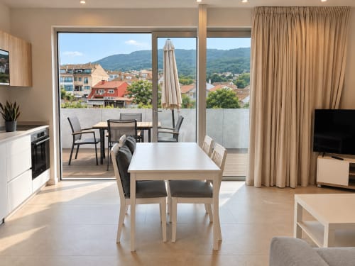 Moderna sala de estar en Baiona con comedor, cocina y balcón con vistas a la ciudad y montañas