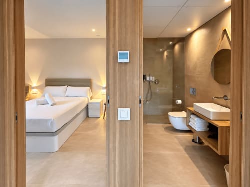 Apartamento moderno en Holibai Baiona con dormitorio, baño ensuite, ambiente cálido, detalles de madera, ropa de cama blanca y ducha