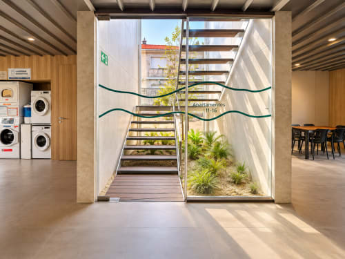Moderno vestíbulo del Holibai Baiona con puertas de vidrio, escalera, áreas verdes e instalaciones de lavandería
