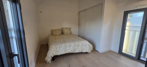 Dormitorio moderno y luminoso con cama queen, armario espejado y puerta de cristal en el apartamento La Perle du Léman en Douvaine